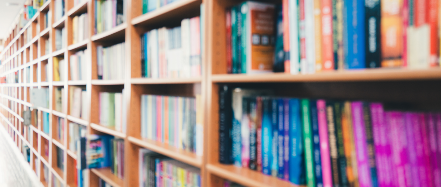 na fotografii widać fragment regału bibliotecznego, zapełnionego kolorowymi książkami.
