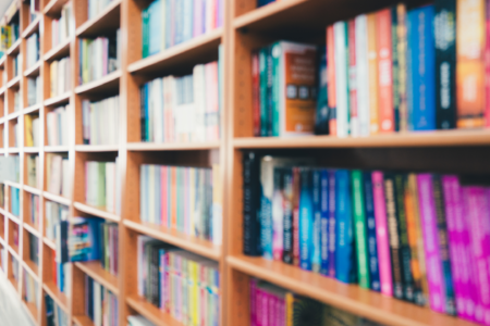 na fotografii widać fragment regału bibliotecznego, zapełnionego kolorowymi książkami.